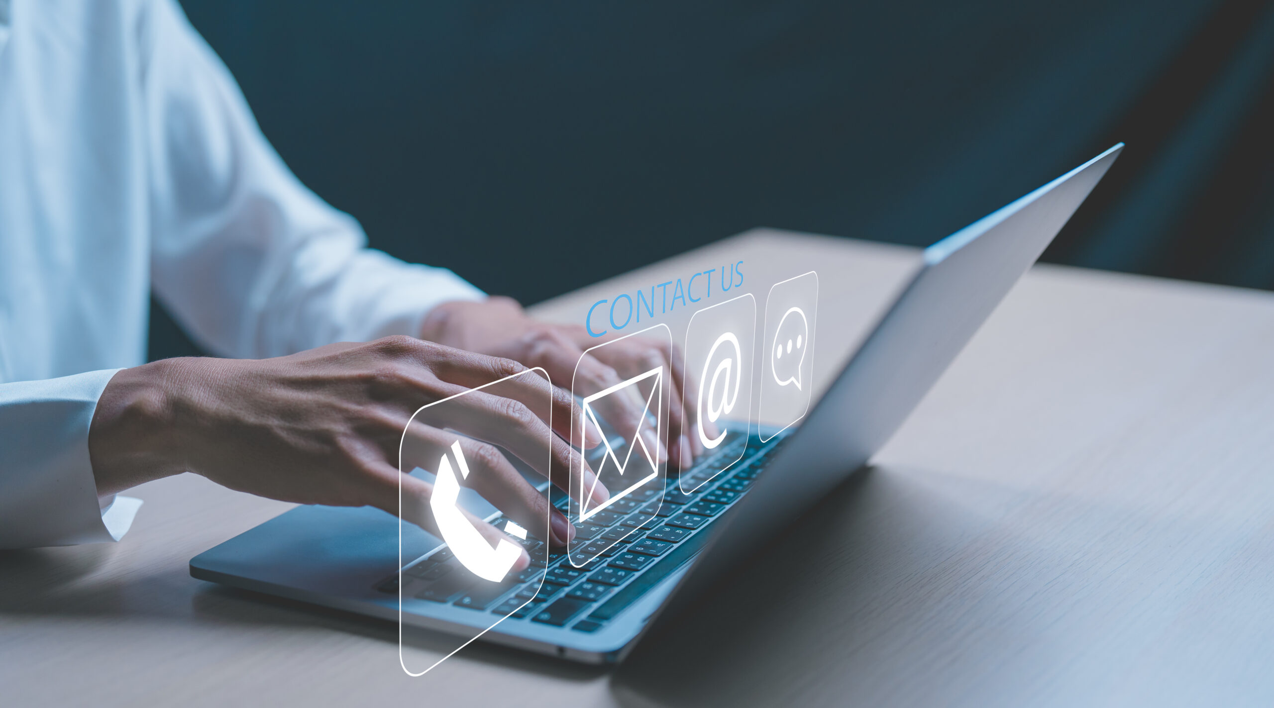 Hender skriver på en bærbar PC med grafiske ikoner for kontaktmetoder som telefon, e-post og chattefunksjon.