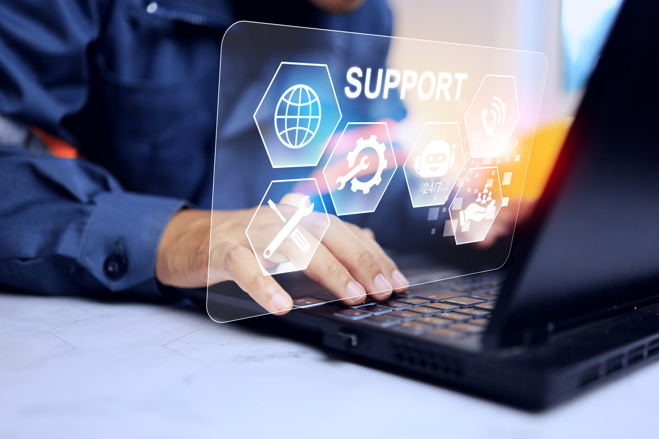 Teknisk støtte og kundeservice i digital verden Person som tilbyr teknisk støtte via laptop med digitale ikoner. En person i skjorte bruker en laptop, med holografiske ikoner for teknisk støtte svevende over tastaturet.